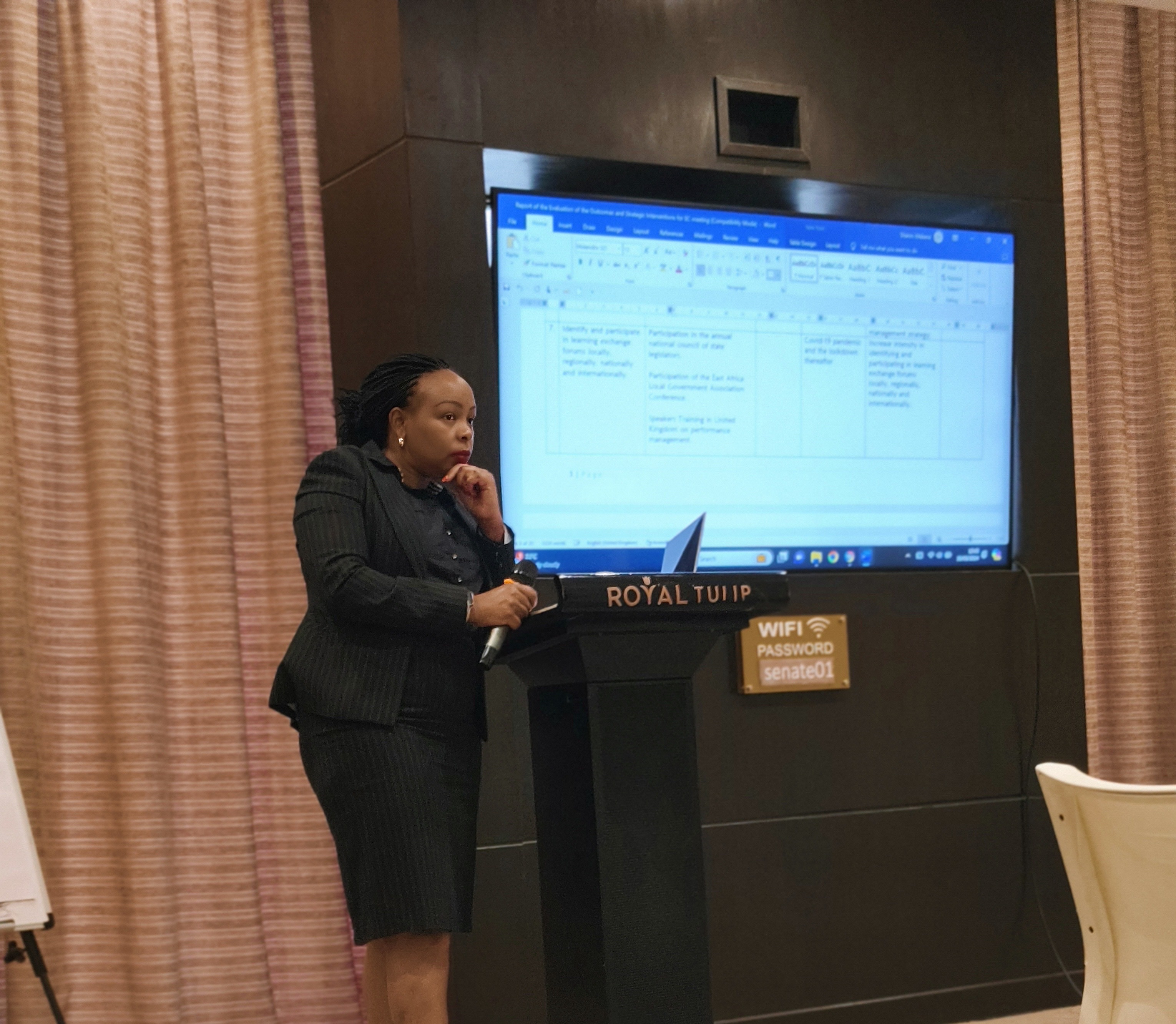 Facilitator at the podium reviewing an evaluation report on screen