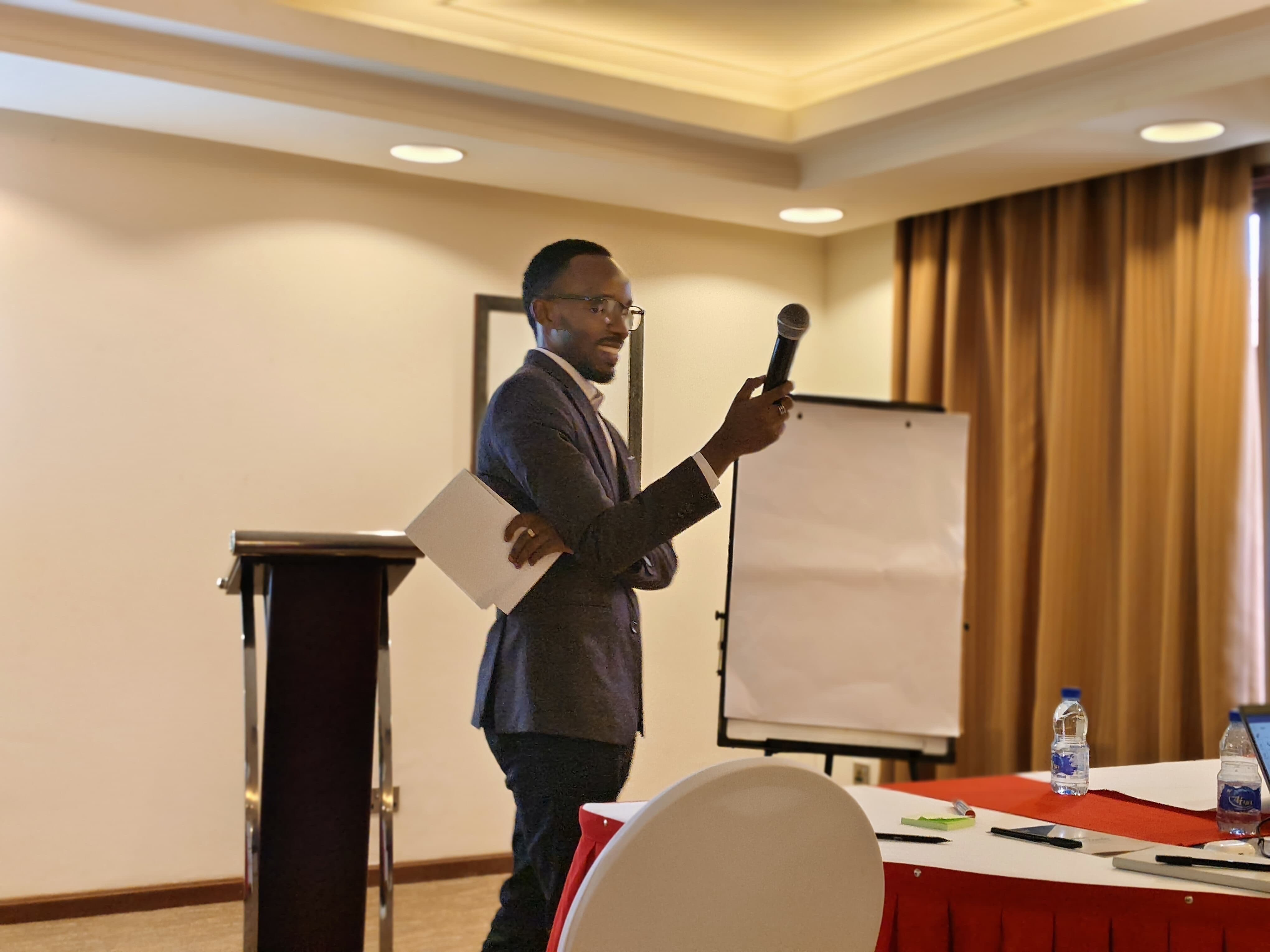 Facilitator holding a microphone and taking questions beside a flip chart