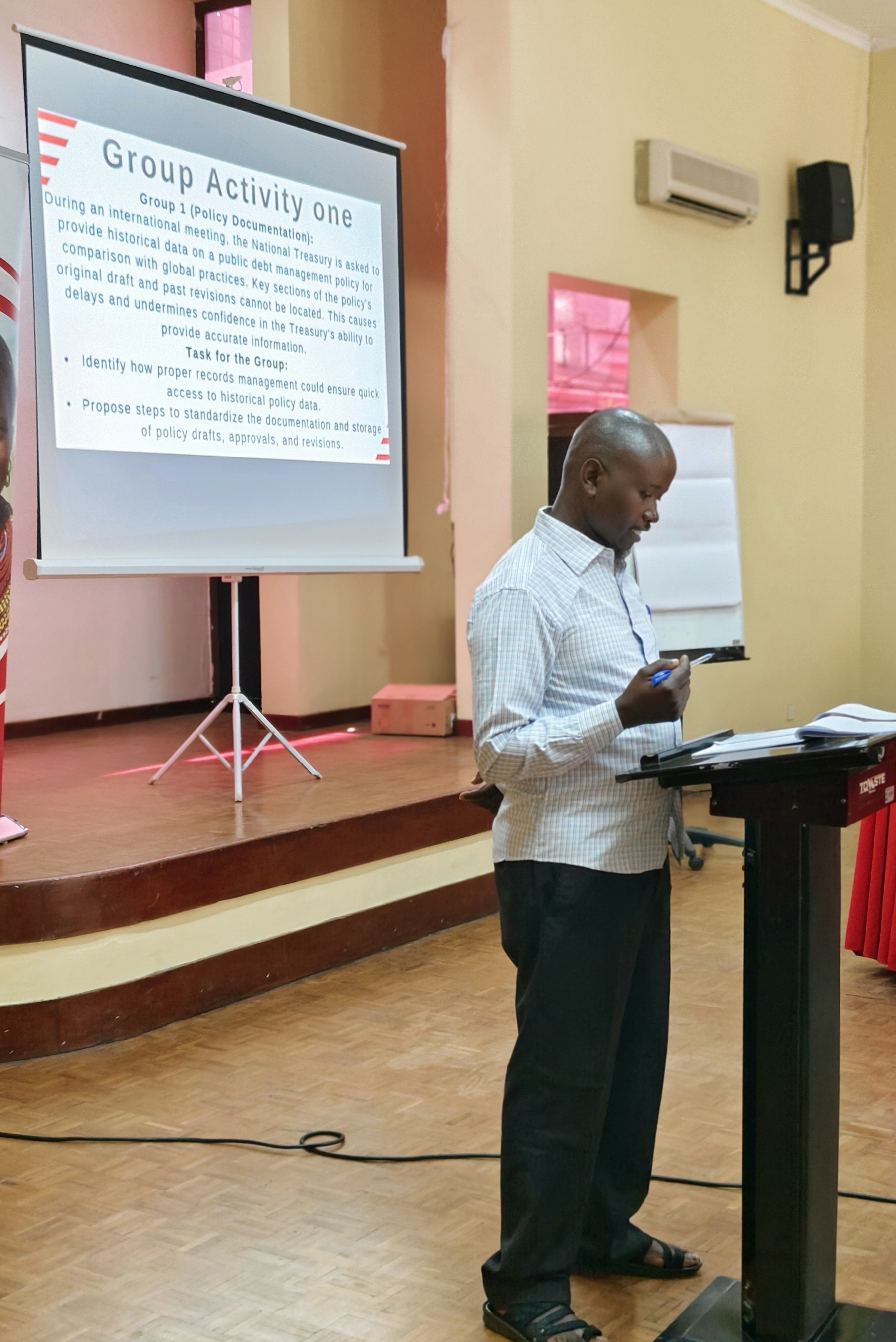 Participant at a lectern presenting his group's response to a policy documentation case study