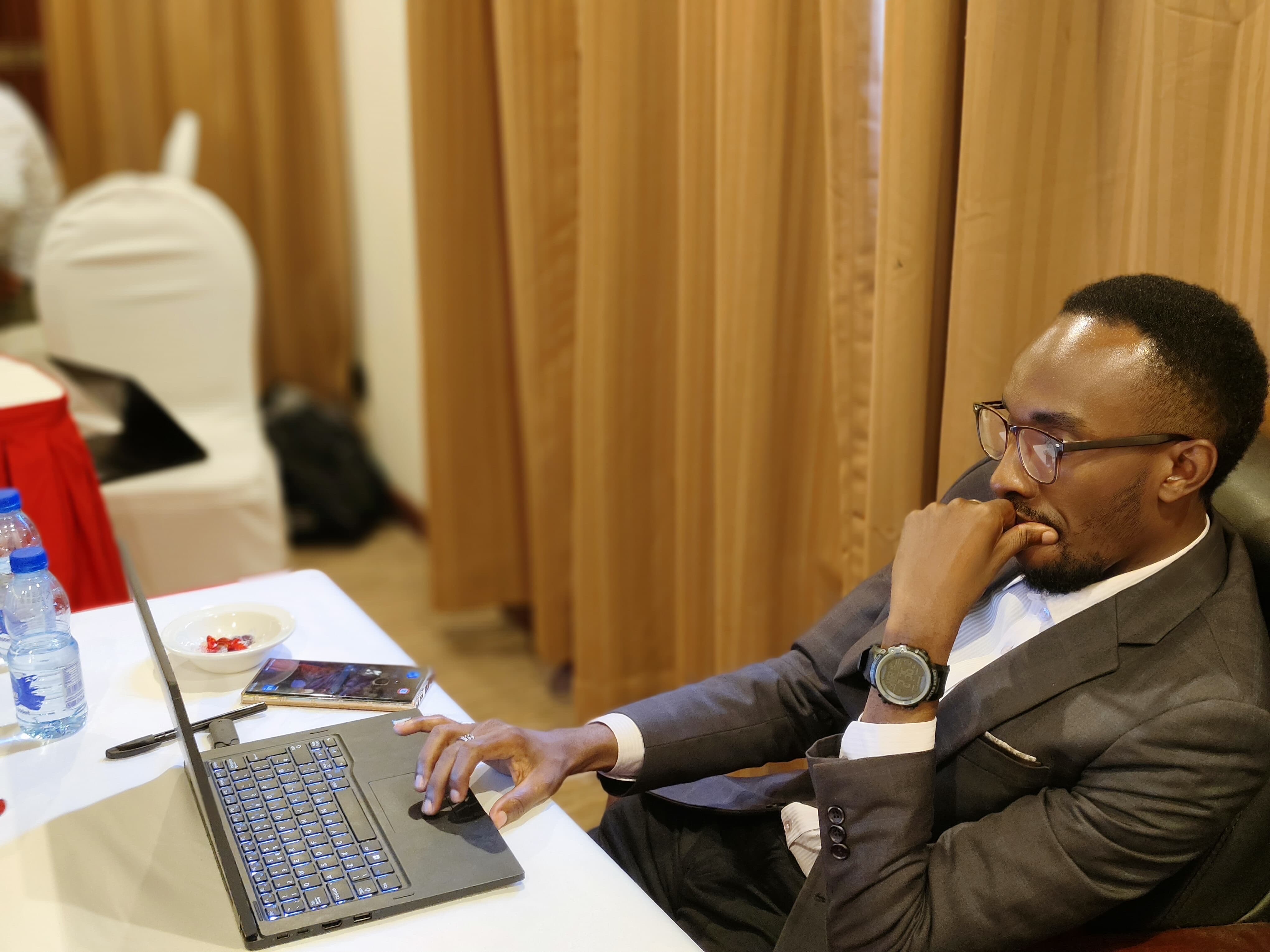 Participant in a suit working thoughtfully through a task on his laptop during a training