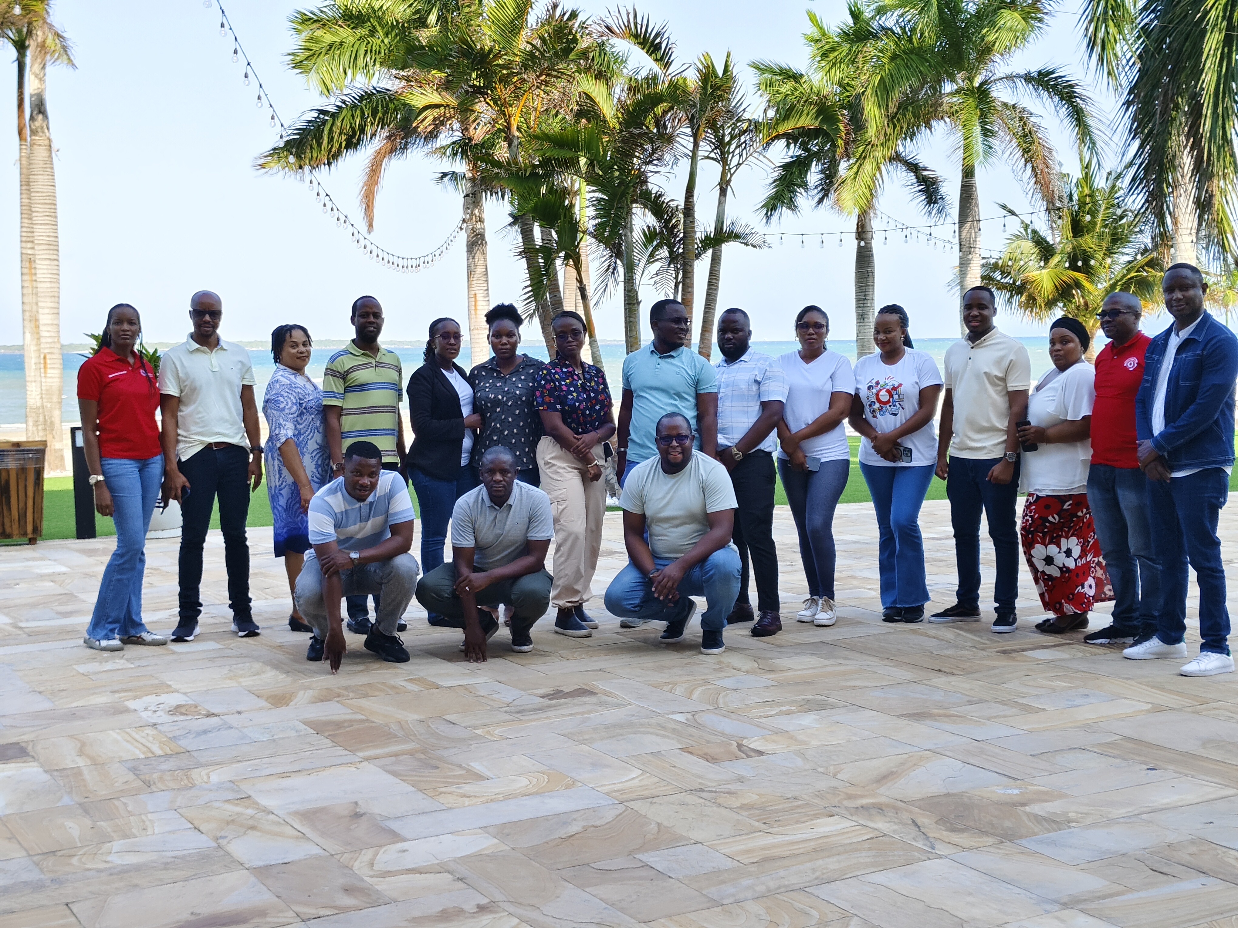 Training participants gathered on a beachfront terrace lined with palm trees