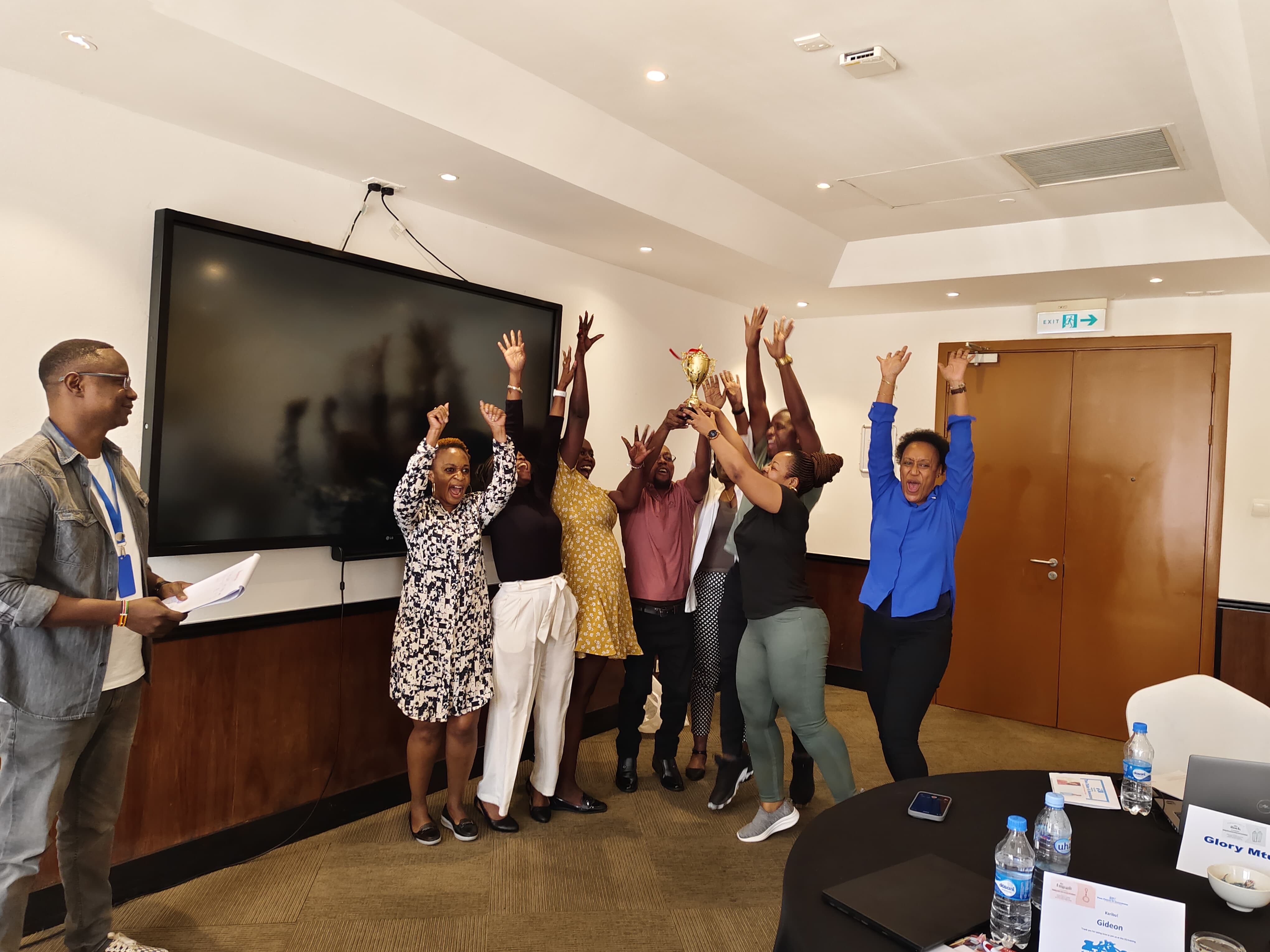 Participants cheering and raising a gold trophy at the close of a training